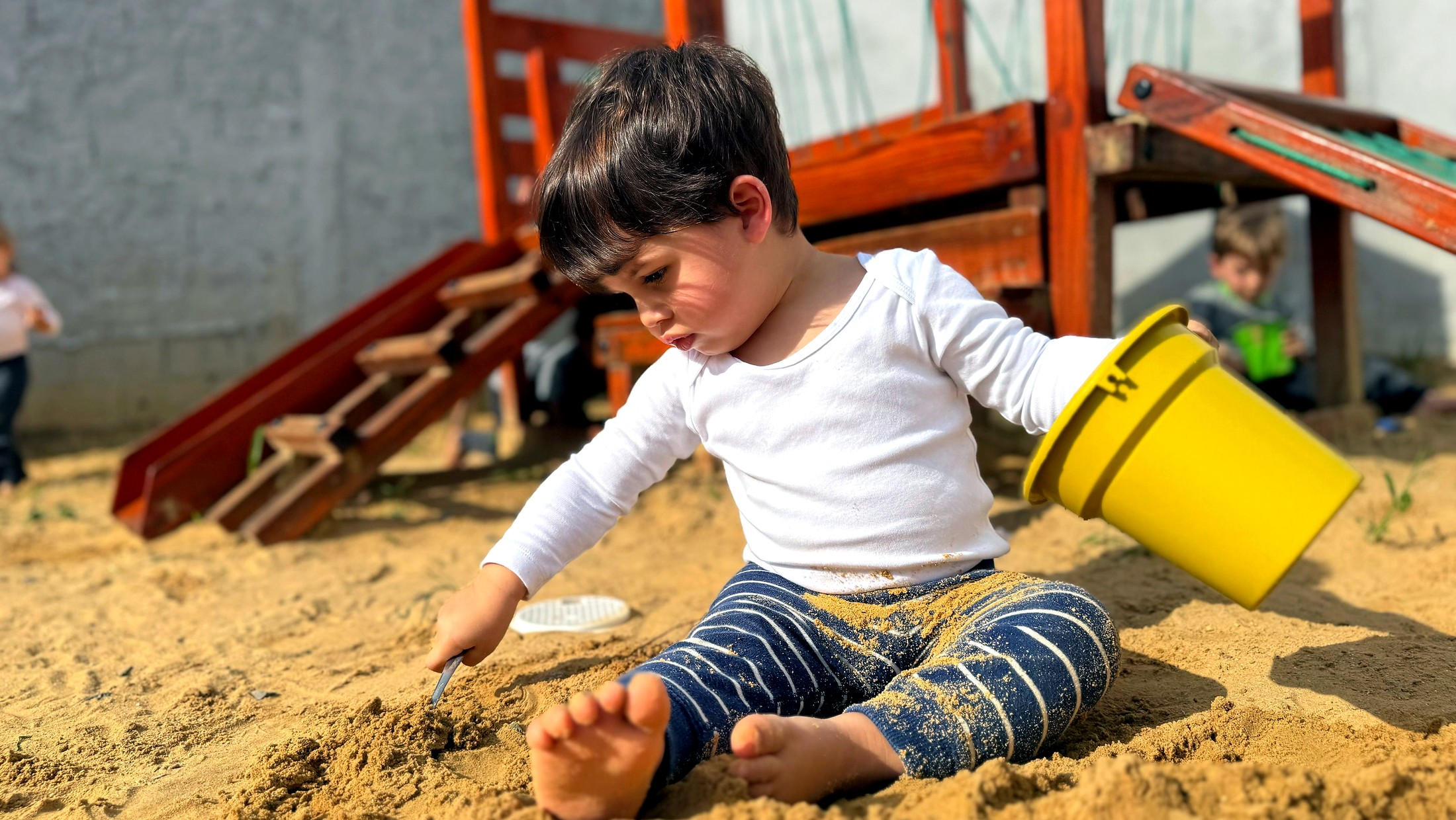 João brincando na areia no espaço externo da Casateliê